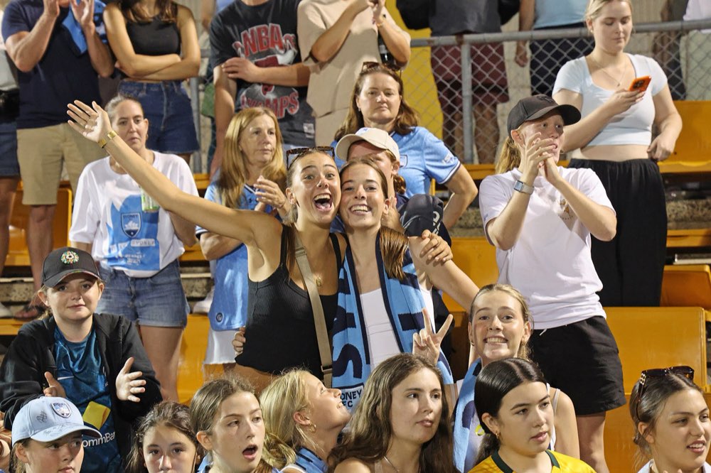 Sydney FC fans cheering together in the stands at night