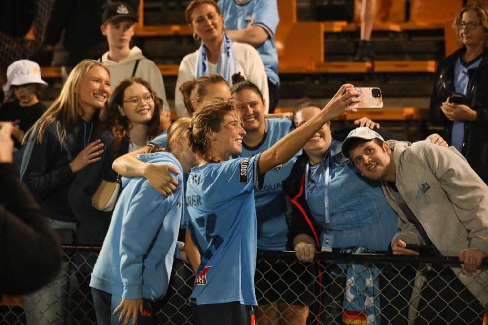 A Sydney FC player taking a selfie with fans after a match